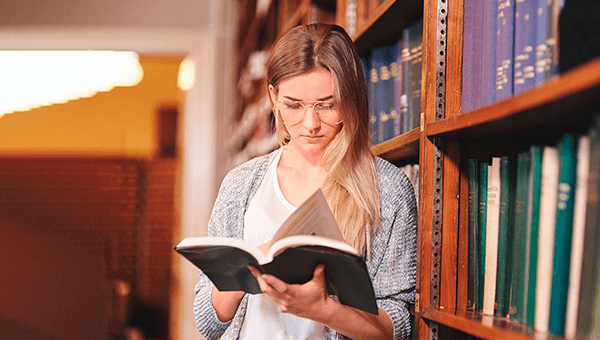Menina na biblioteca lendo livro